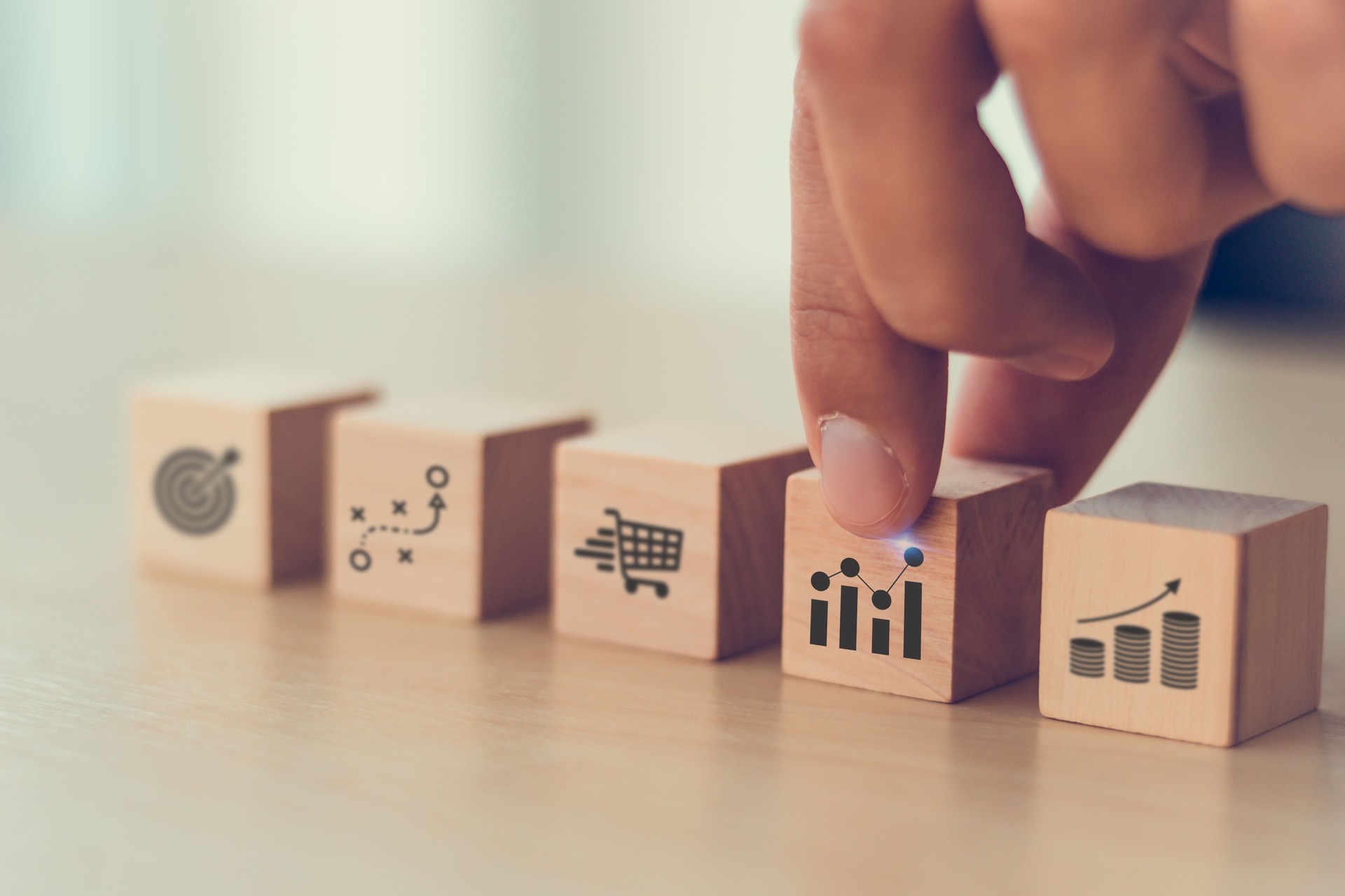 Sales strategy and performance concept. A hand arranging wooden blocks with icons symbolizing sales target, data analytics, strategic planning, sales team management and sales performance.